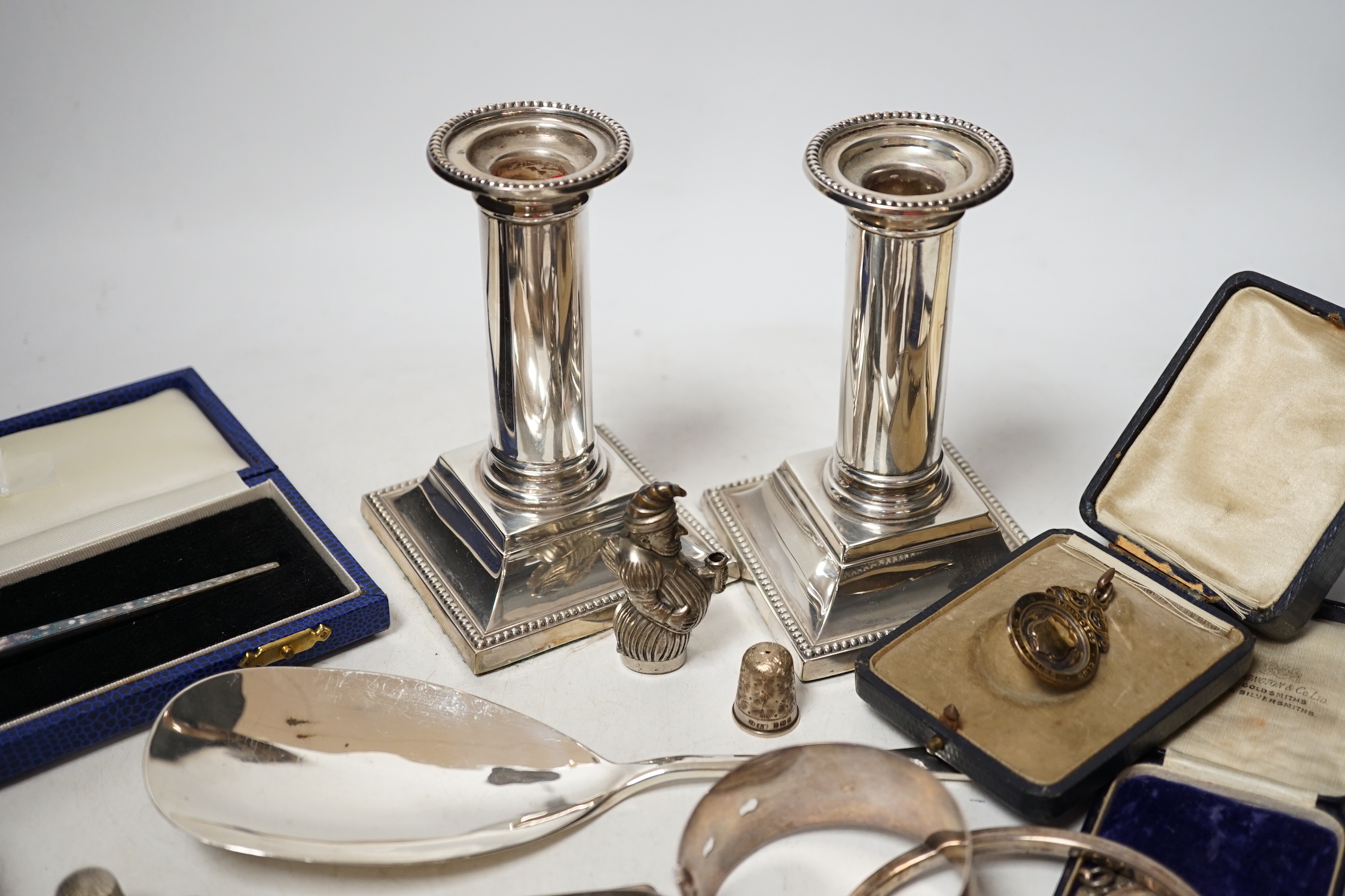 Sundry small silver including a cased preserve spoon, by Albert Edward Jones, a pair of mounted dwarf candlesticks, serving spoon, thimbles, napkin ring etc.